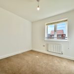 Empty room with carpet and window overlooking houses.