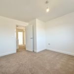 Empty carpeted room with open door and light bulb.