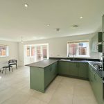 Modern kitchen with green cabinets and bright lighting.