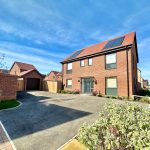 Modern brick house with solar panels in sunny neighbourhood.