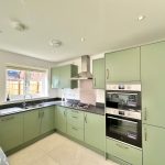 Modern kitchen with green cabinets and appliances.