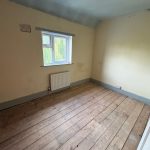Empty room with wooden floor and single window.