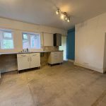 Empty kitchen space with white cabinets and tiled floor.