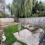Back garden with grass and wooden fence.