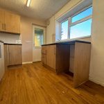 Modern kitchen with wooden cabinets and flooring.