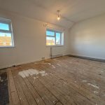 Empty room with wooden floors and white walls.