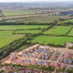 Aerial view of housing development and green fields.