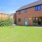 Back garden of a brick house with patio doors.