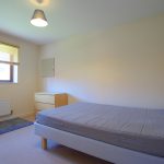Bright bedroom with bed and chest of drawers.