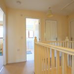 Bright hallway with white railings and doors.