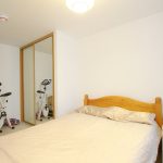 Bedroom with exercise bike and mirrored wardrobe.
