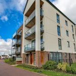 Modern apartment building with balconies and greenery.