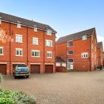 Red brick residential building with parking area.