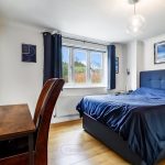 Modern bedroom with desk and large window.