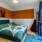 Bright bedroom with bed, keyboard, and guitar.