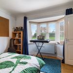 Cosy bedroom with keyboard and bright window view.