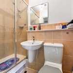 Compact bathroom with shower, sink, and toilet.