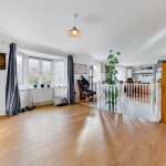 Spacious room with wooden floor and large windows.