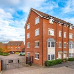 Red brick apartment building with gated parking area.