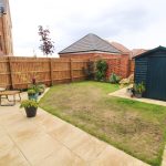 Modern garden with patio and wooden shed.