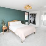 Modern bedroom with green accent wall and wooden bed.
