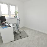 Minimalist home office with white furniture and carpet.