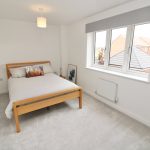 Modern bedroom with window and wooden bed frame.