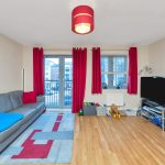 Modern living room with red curtains and grey sofa.