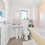 Modern bathroom with white fixtures and blue curtains.