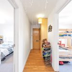 Hallway with two bedrooms, bunk bed and shoe rack.