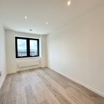Empty room with wooden flooring and large window