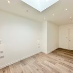 Empty room with wooden floor and skylight.
