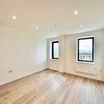 Bright empty room with wooden floor and large windows.
