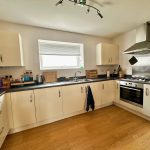 Modern kitchen with appliances and wooden flooring.