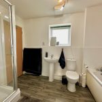Modern bathroom with shower, bathtub, and wooden floor.