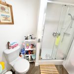 Bathroom with shower, toilet, and toiletries shelf.