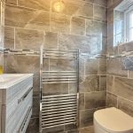 Modern bathroom with grey tiles and towel radiator.