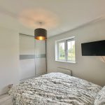 Modern bedroom with patterned bedspread and wall-mounted TV.