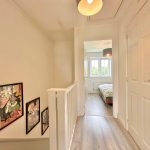Bright hallway with framed art and bedroom view.
