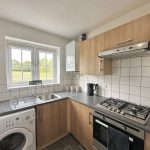 Modern kitchen with oven, washer, and cabinets.