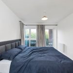 Modern bedroom with large bed and garden view.