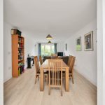 Modern dining area with wooden table and chairs.