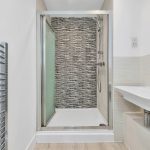 Modern bathroom with glass shower and sink.