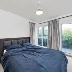 Bright bedroom with large window and double bed.