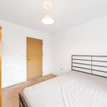 Simple bedroom with bed, wardrobe, and wooden door.