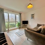 Bright living room with sofa, plants, and large window.