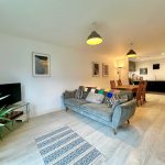 Modern open-plan living room and kitchen with decor.