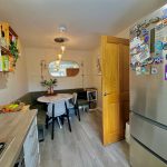 Modern kitchen with dining area, fridge magnets visible.