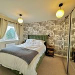Stylish bedroom with patterned wallpaper and double bed.