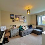 Cosy living room with sofa, keyboard, and wall art.
